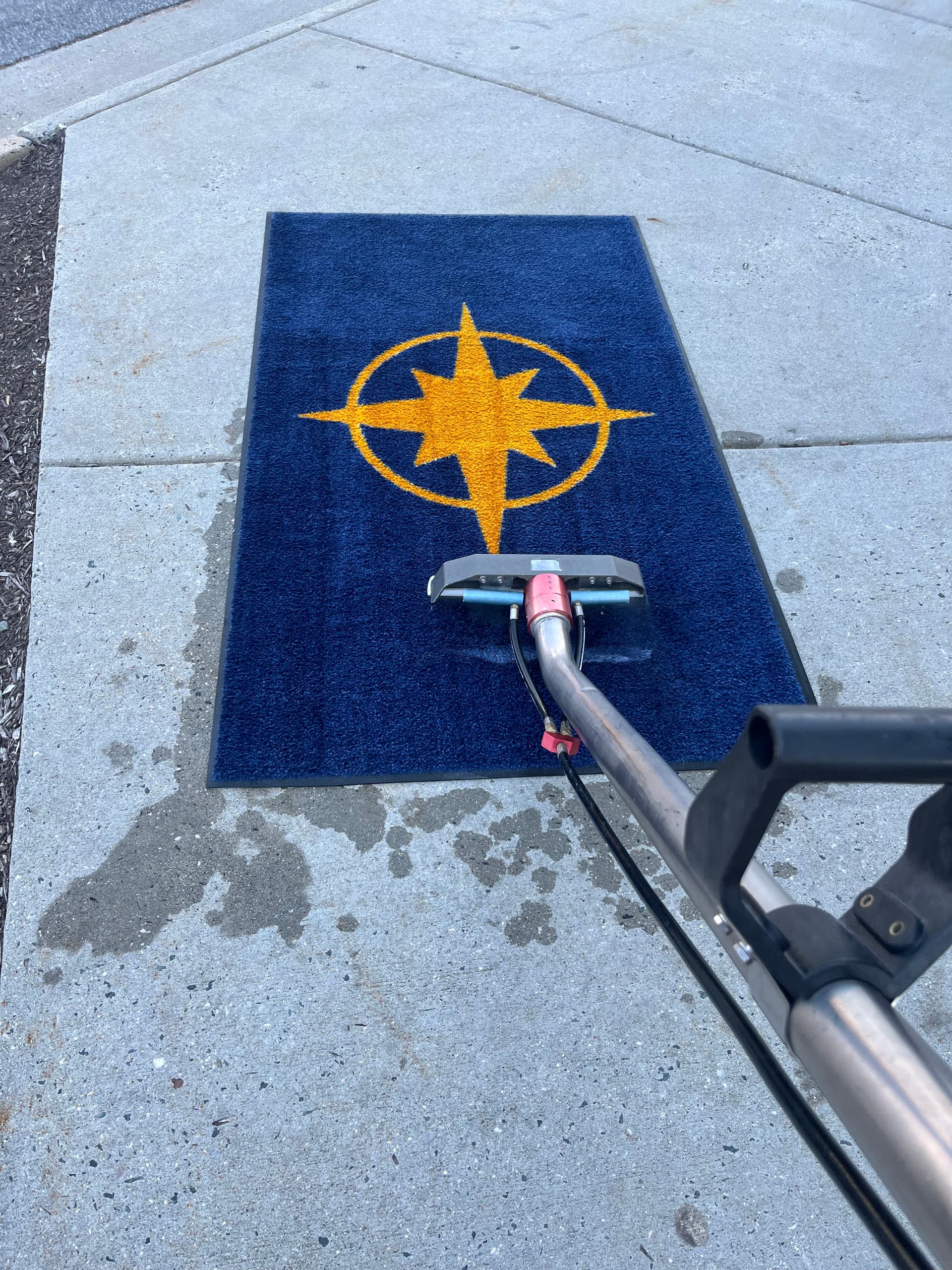 Blue entry mat with a yellow compass motif and an extraction tool