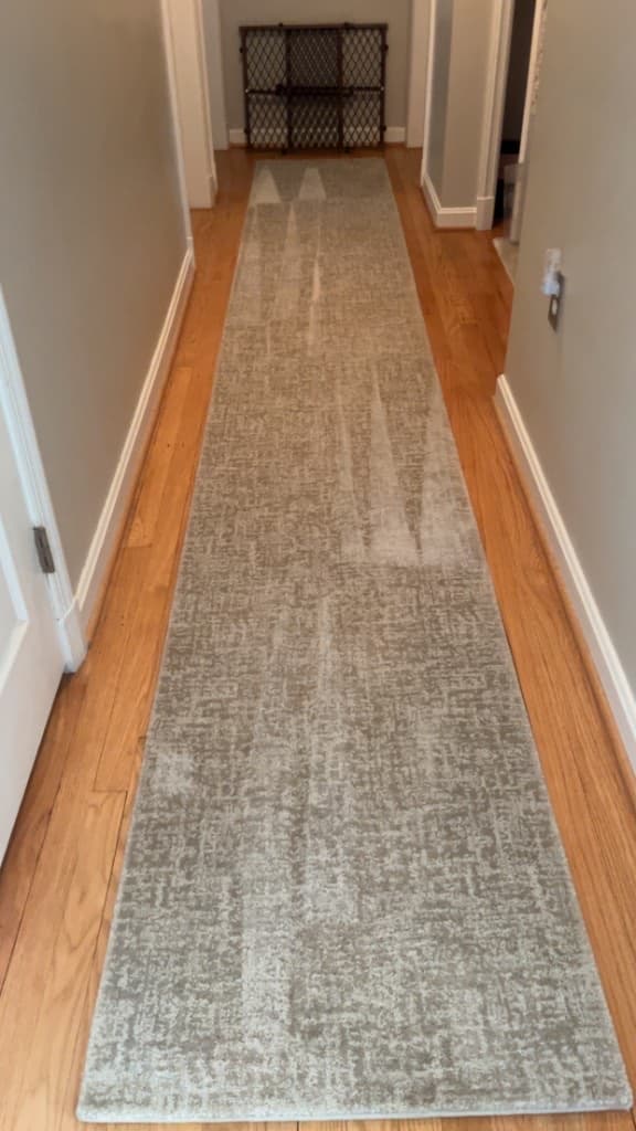 Long pale patterned runner in a narrow hallway with wood floor edges