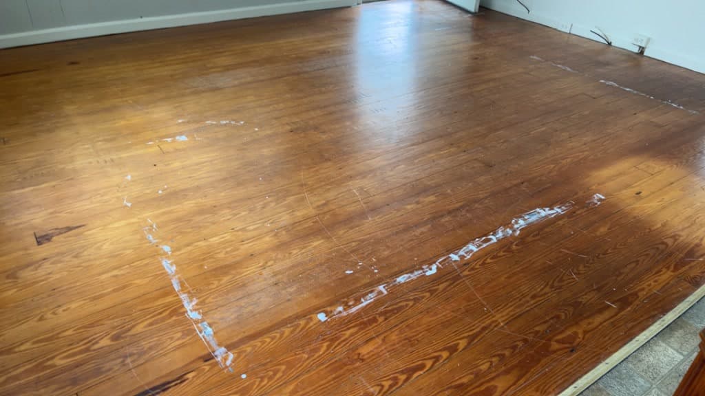 Broad wood floor with a pale rectangular outline and linear marks