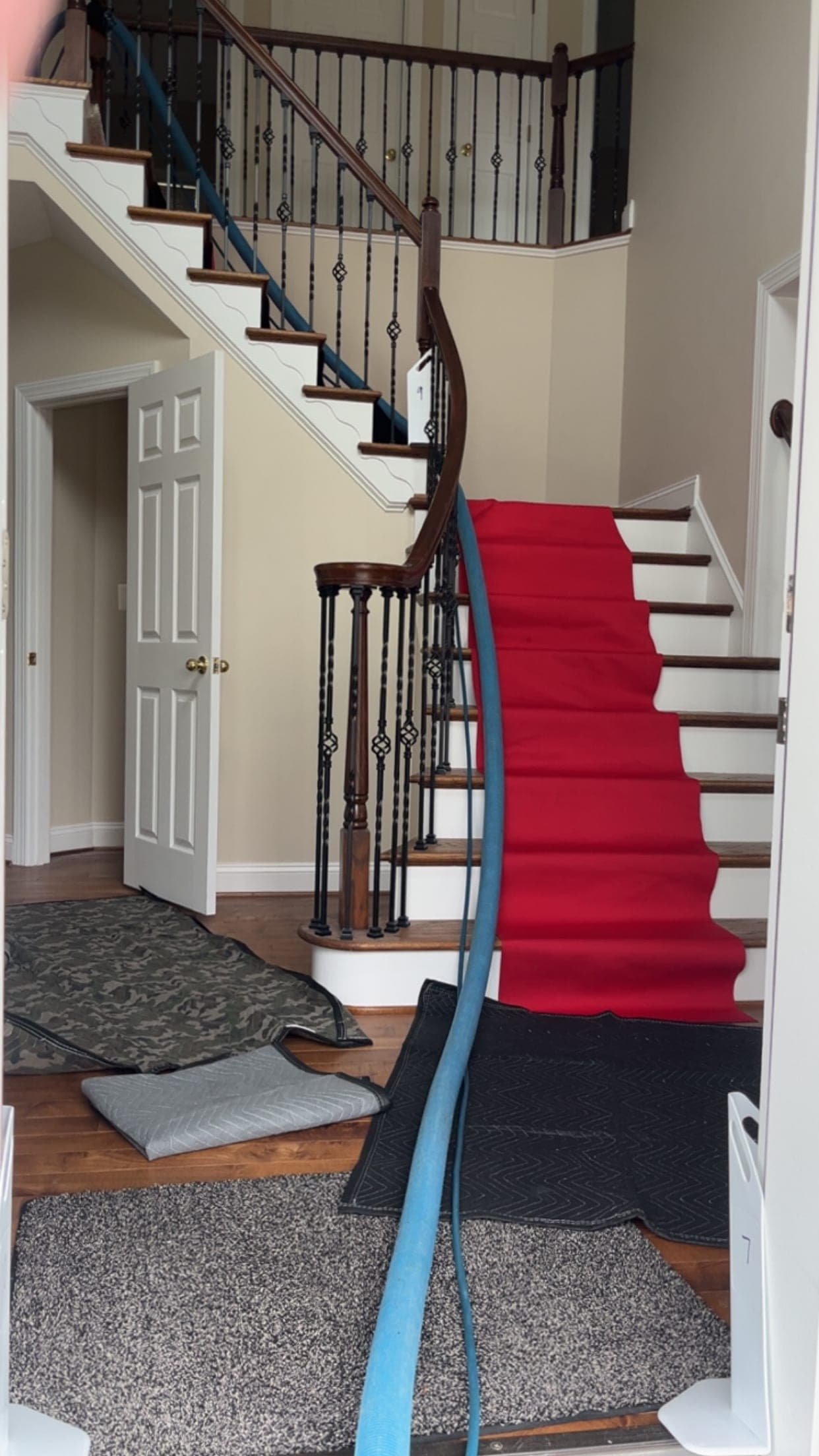 Staircase protected with a red runner and a blue hose during setup