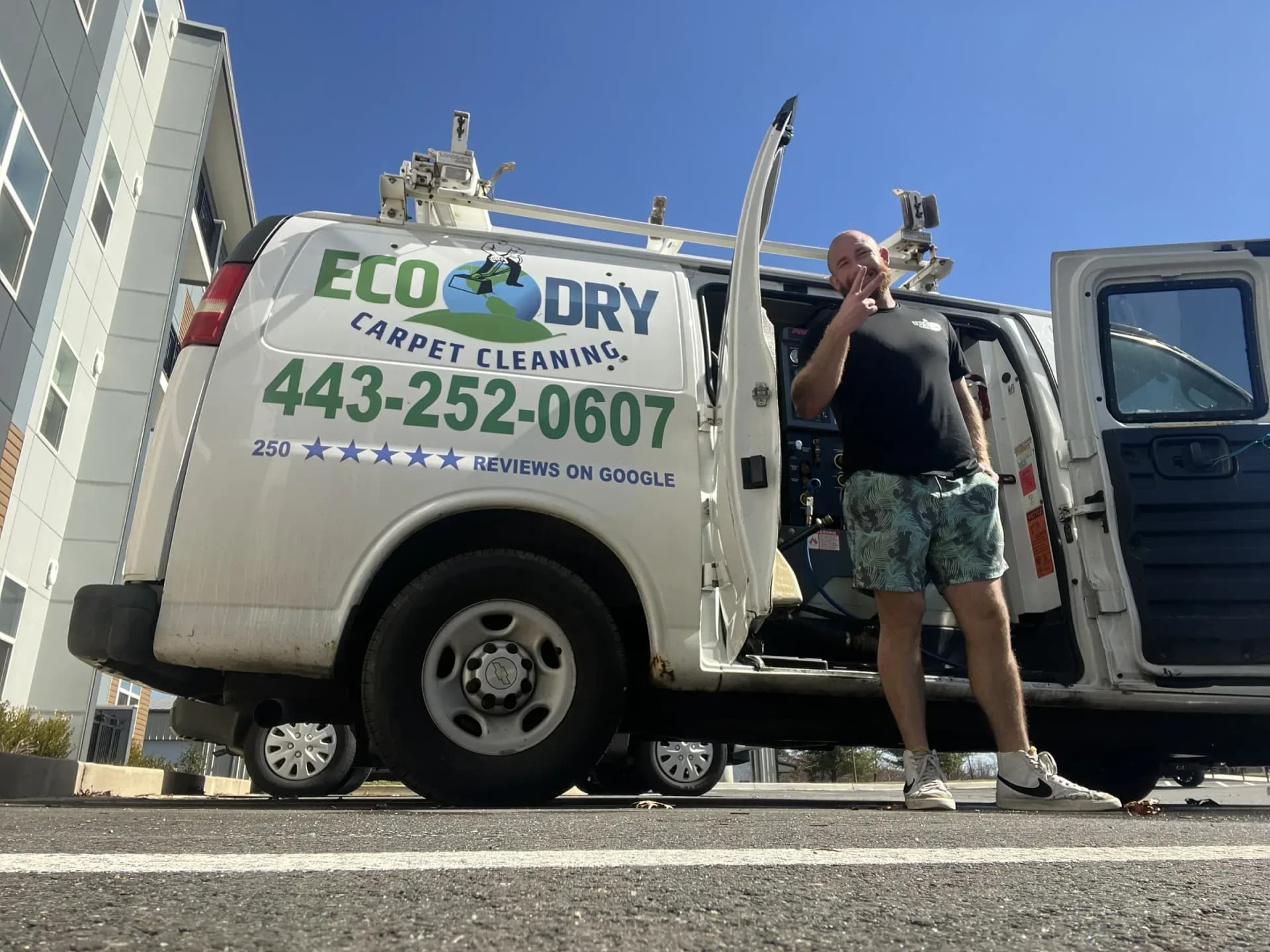 Technician holding extraction equipment beside an Eco-Dry van near a multi-story building