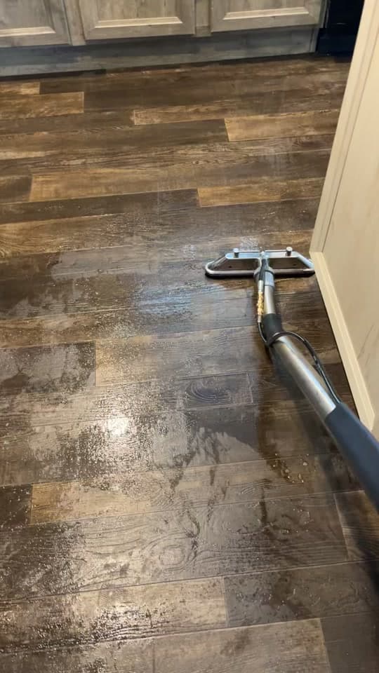 Extraction tool on dark wood-look vinyl planks with wet sheen