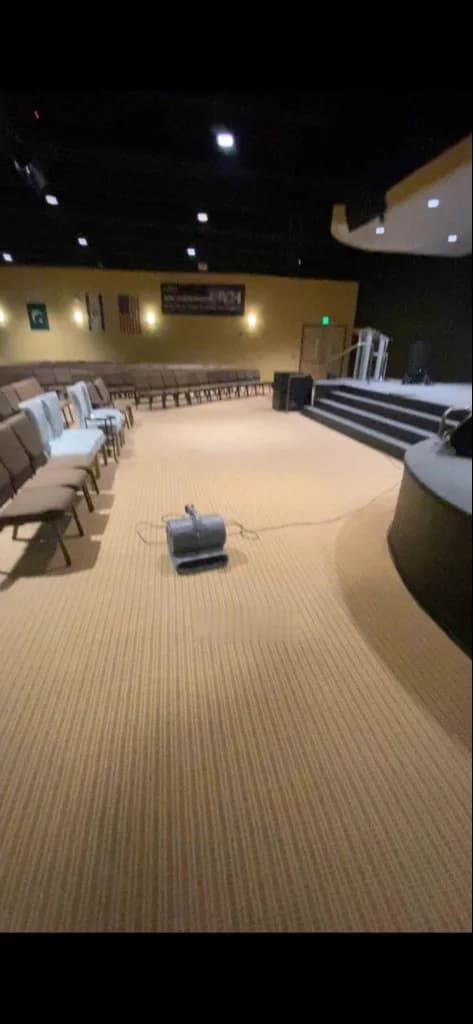 Carpeted meeting or auditorium space with rows of chairs and an air mover