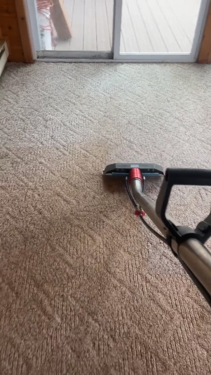 Extraction wand on beige carpet beside a sliding exterior door