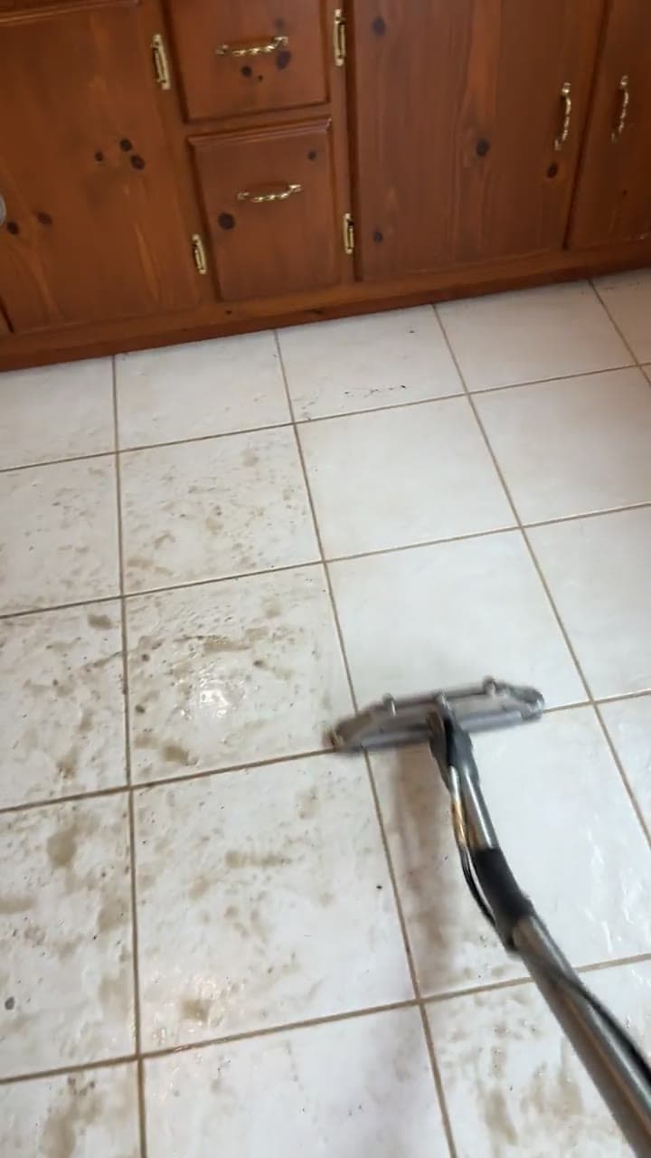 Extraction head on white square floor tiles beside wood cabinetry