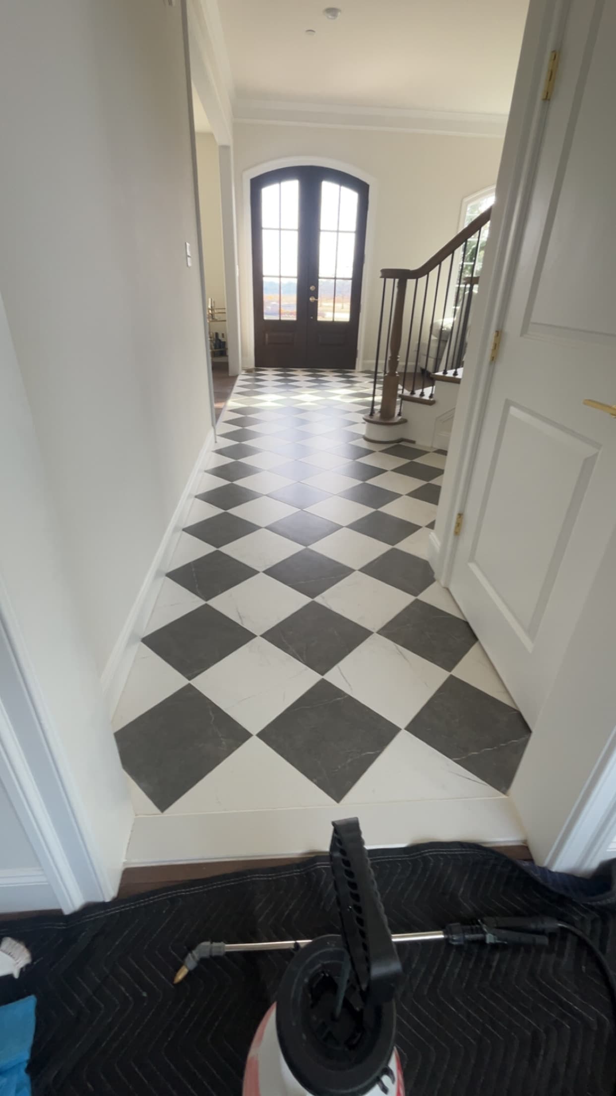 Black and white checkerboard tile in an entry hall with wood stairs